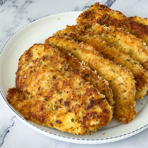 Parmesan crusted chicken on a white plate.
