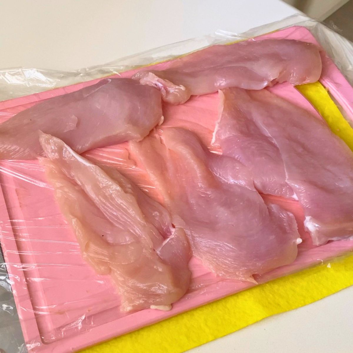 Mashing the chicken breast cutlets with a mullet.