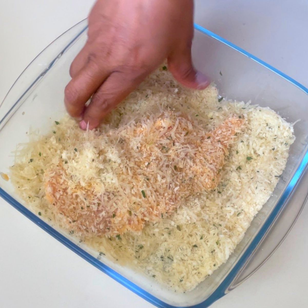 Coating chicken with Parmesan.