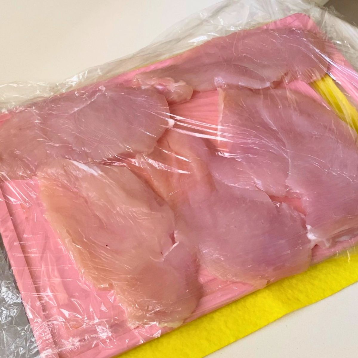 Pounding the chicken breast cutlets for breading.
