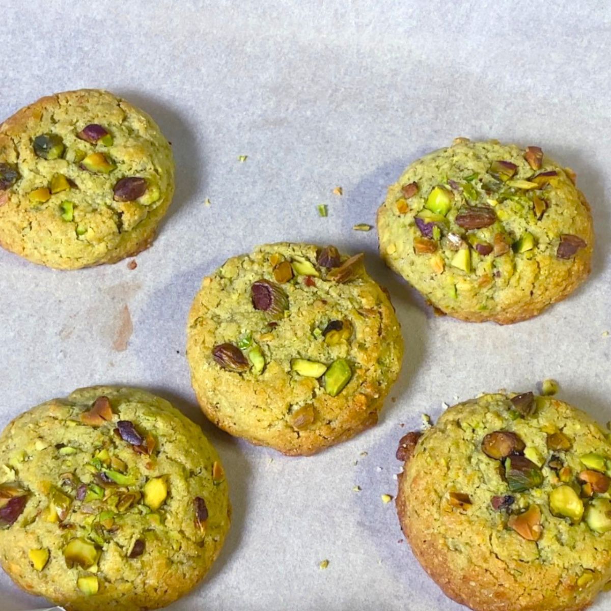A baking tray with baked pistachio cookies.