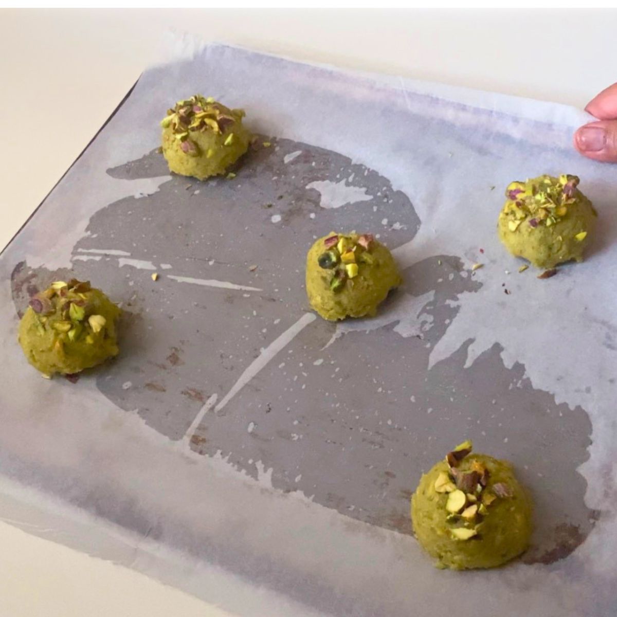 A baking tray with pistachio cookie dough.