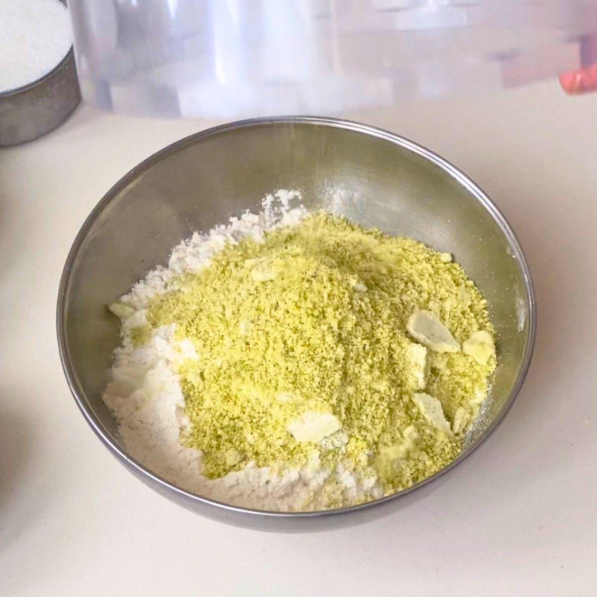 Combining flour and ground pistachios in a bowl.