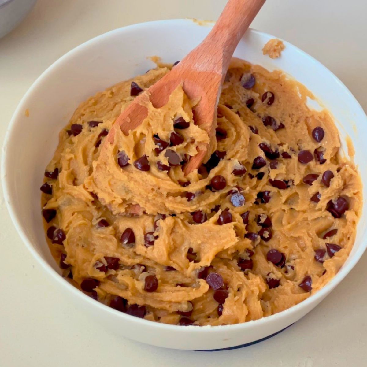 A white bowl with fresh chocolate chip cookies.