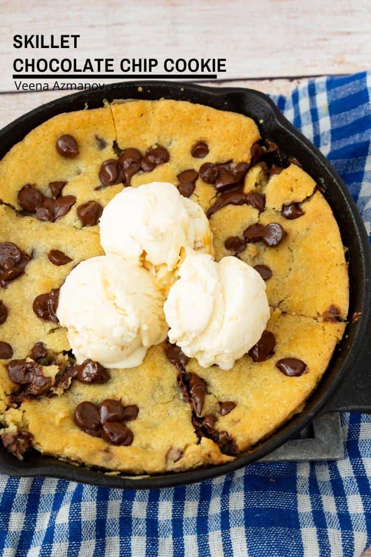 A giant chocolate chip cookie in a skillet, with vanilla ice cream on top.