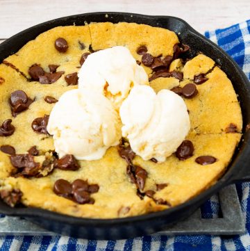 A giant chocolate chip cookie in a skillet, with ice cream on top.
