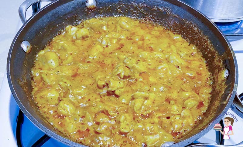 A pan with cooking chicken enchilada.