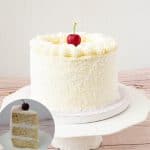 A frosted coconut layer cake on a cake stand.