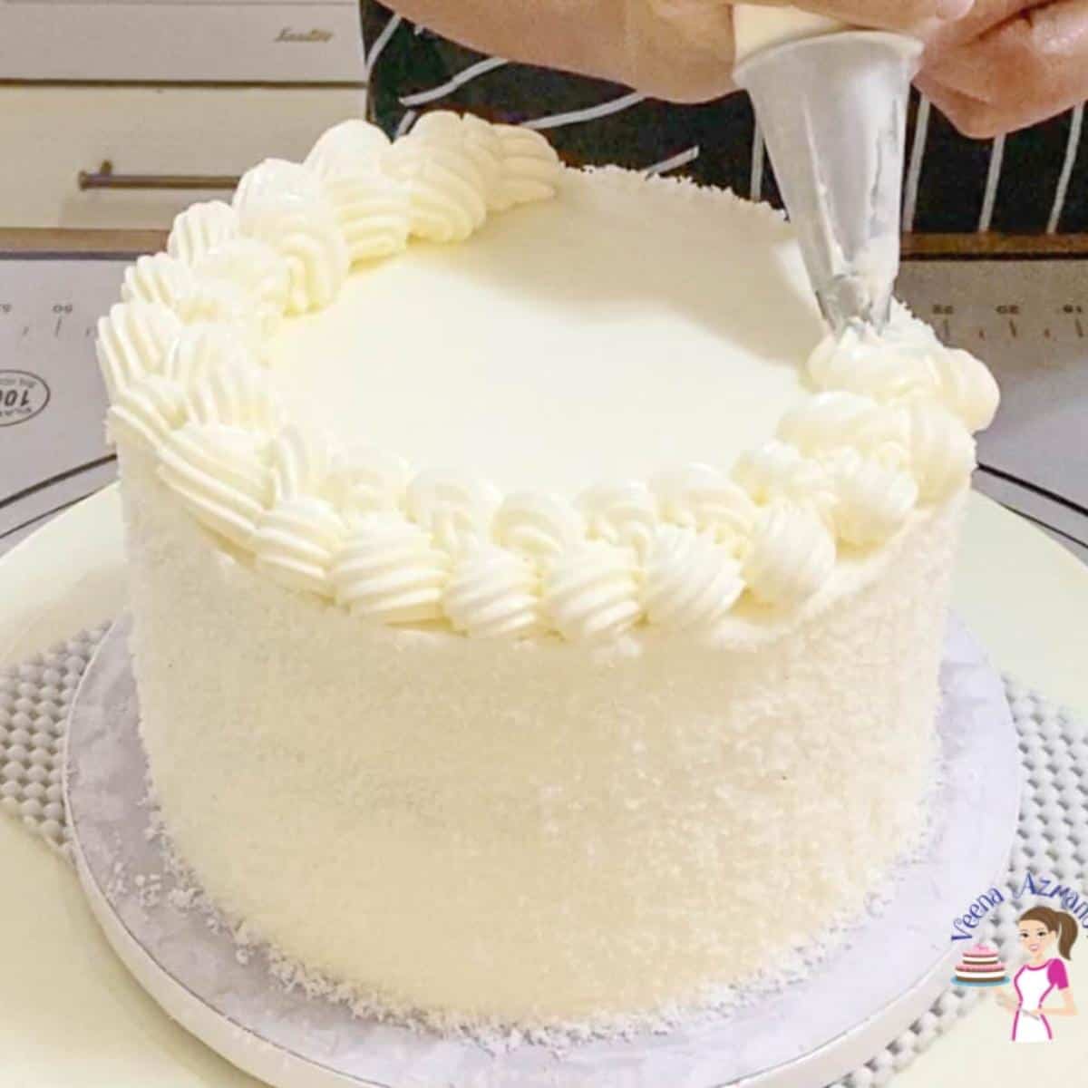 Piping frosting on a coconut cake.