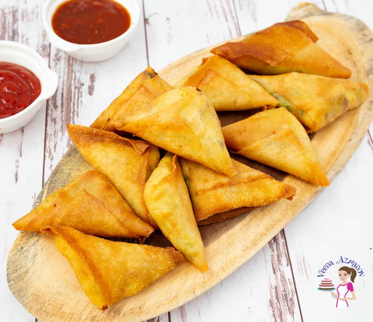 A stack of samosas on a wooden board.