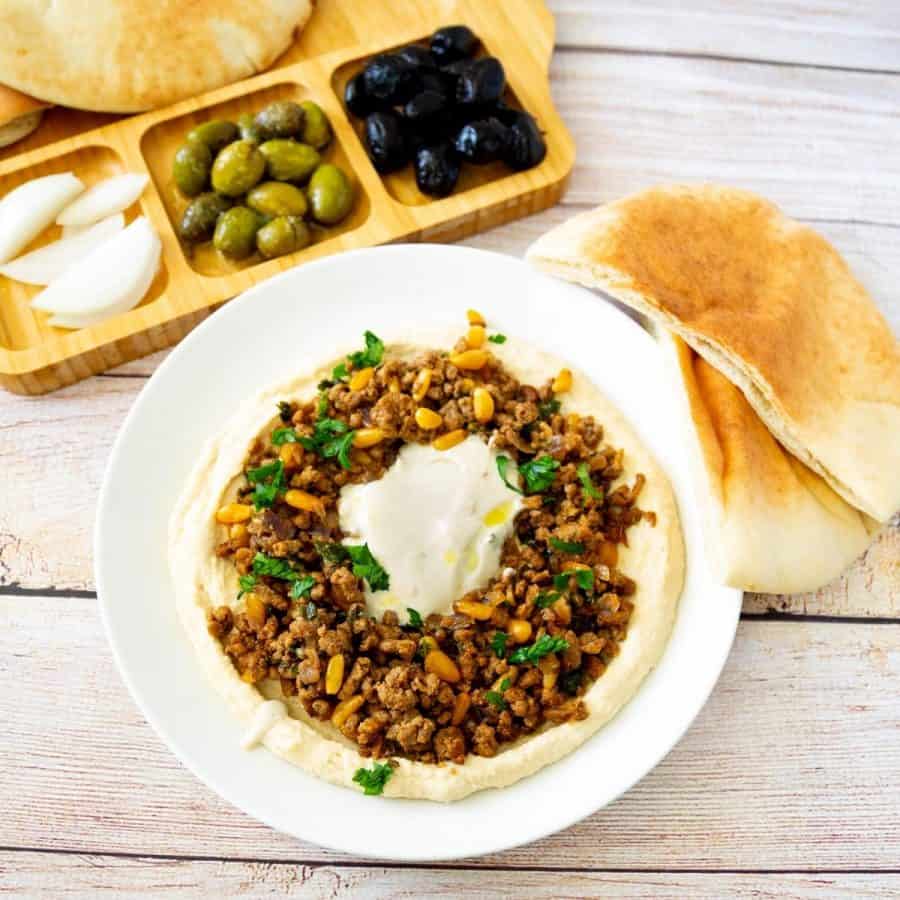 A plate with ground beef and hummus.
