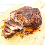 Sliced brisket with red wine gravy on a wooden board.