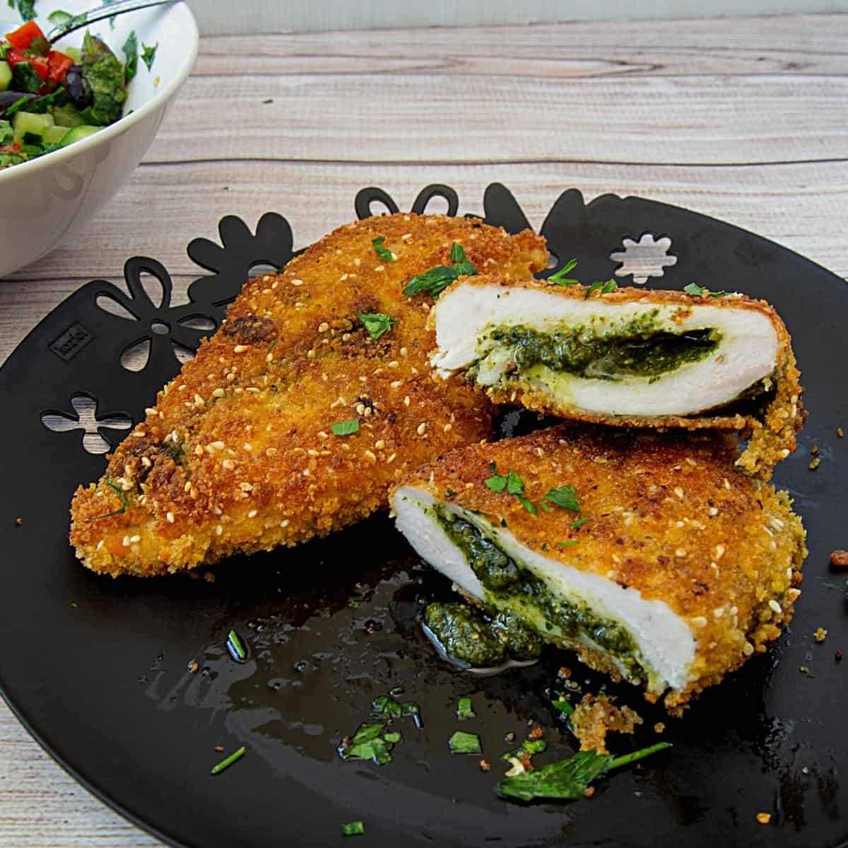 A plate with stuffed and breaded chicken breast.
