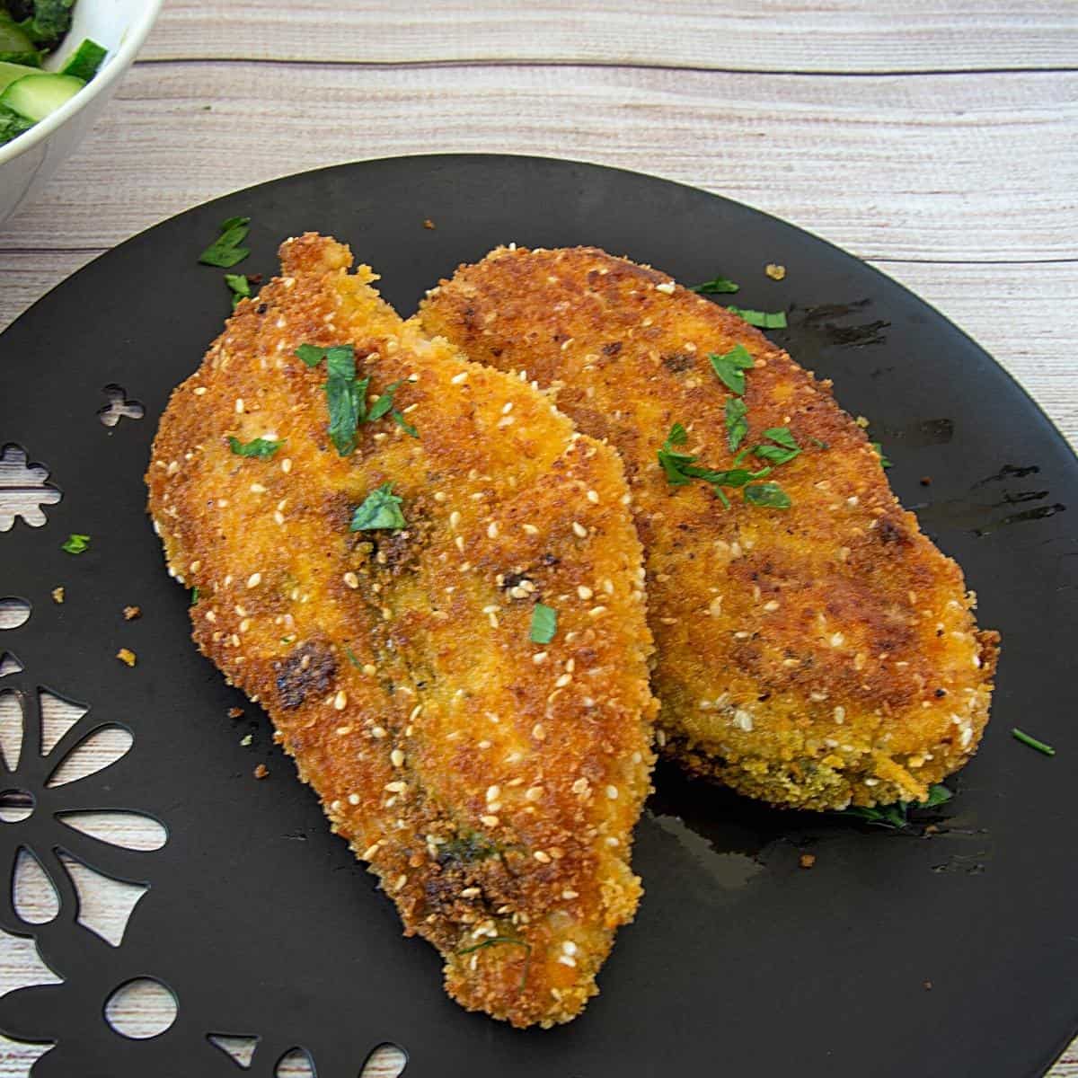 Two breaded chicken breast on a plate.