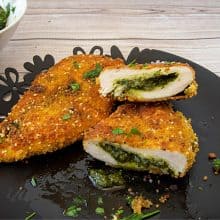 A plate with breaded chicken breast stuffed with pesto.