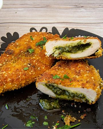 A plate with breaded chicken breast stuffed with pesto.