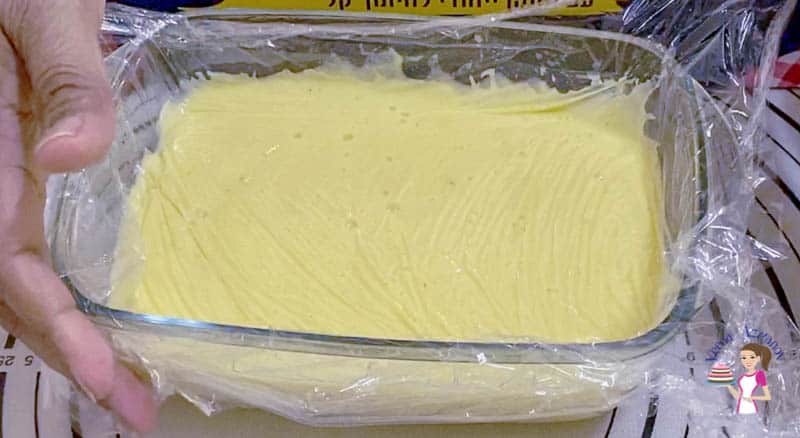 A baking dish with vanilla pastry cream covered by cling wrap.