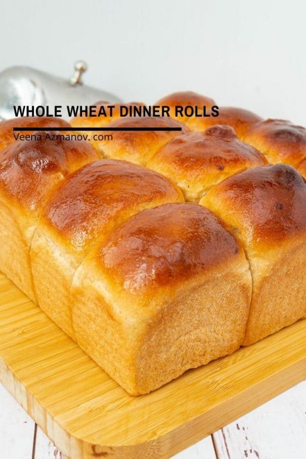 Whole wheat dinner rolls on a wooden board.