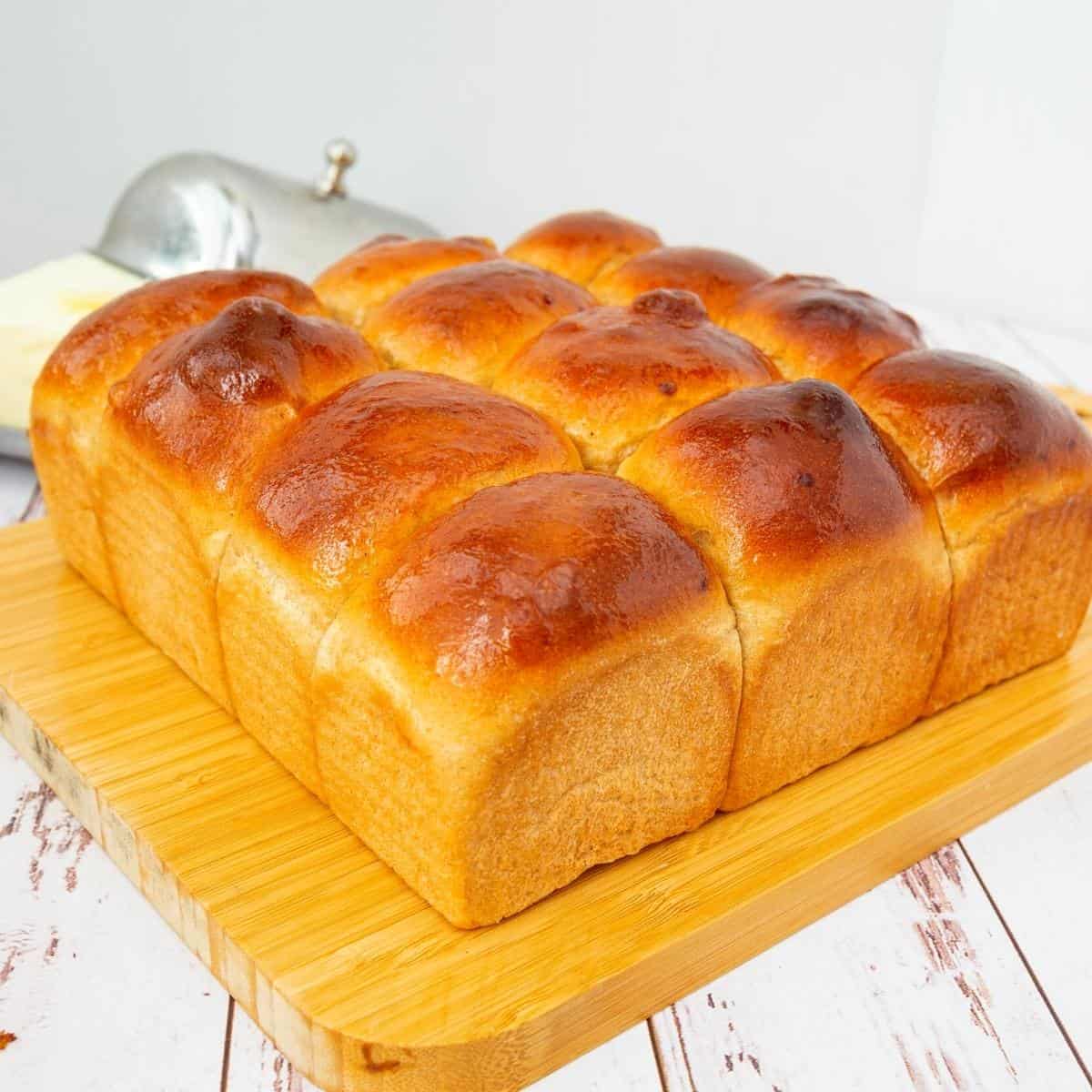 A slab of whole wheat dinner rolls on the table.