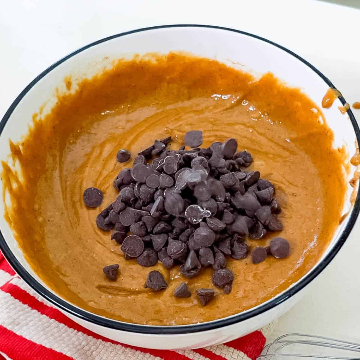 Rich chocolate chip cookie dough in a mixing bowl, ready for baking or snacking.
