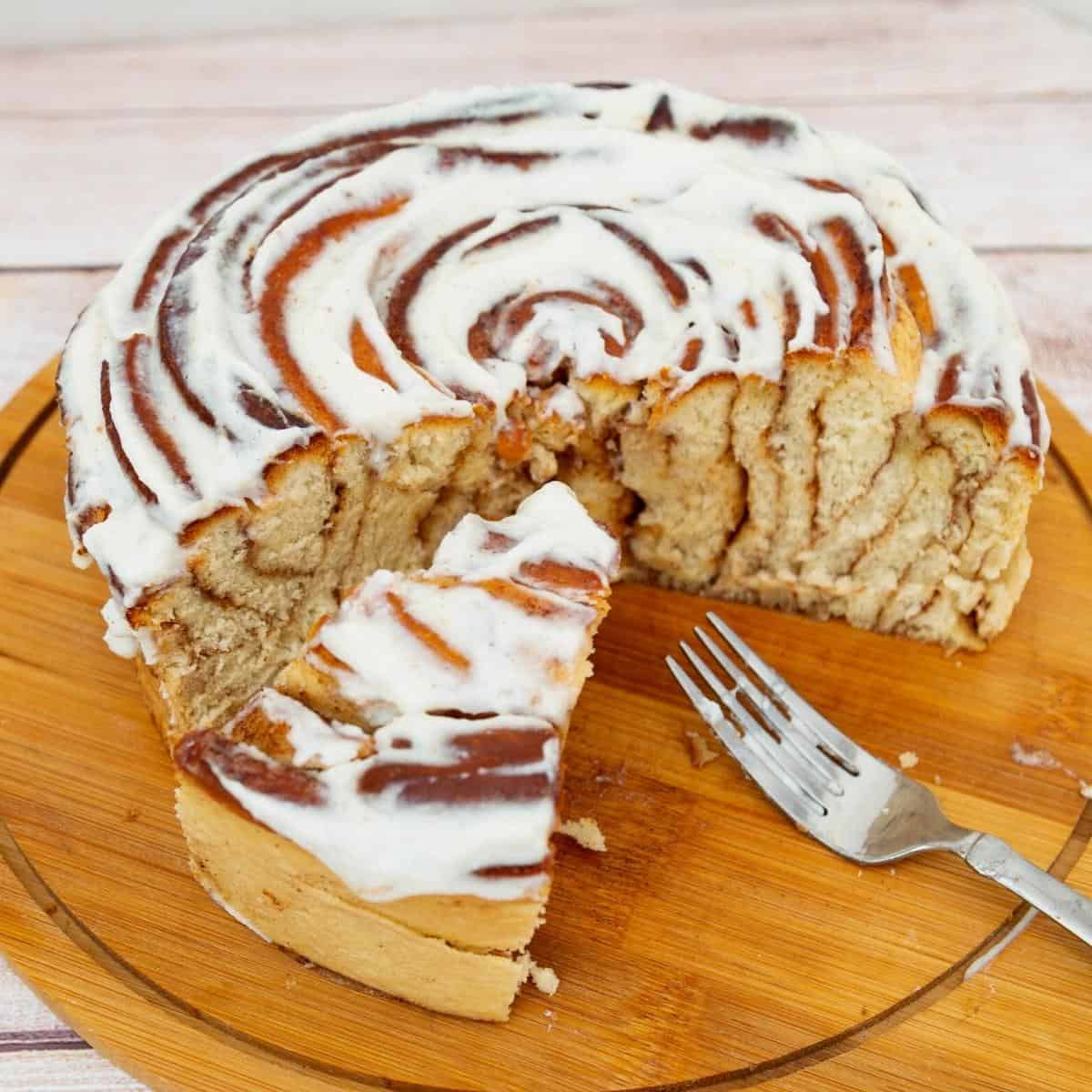 A large giant size cinnamon roll on a wooden board.