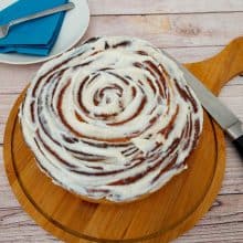 A giant cinnamon roll on a wooden board.