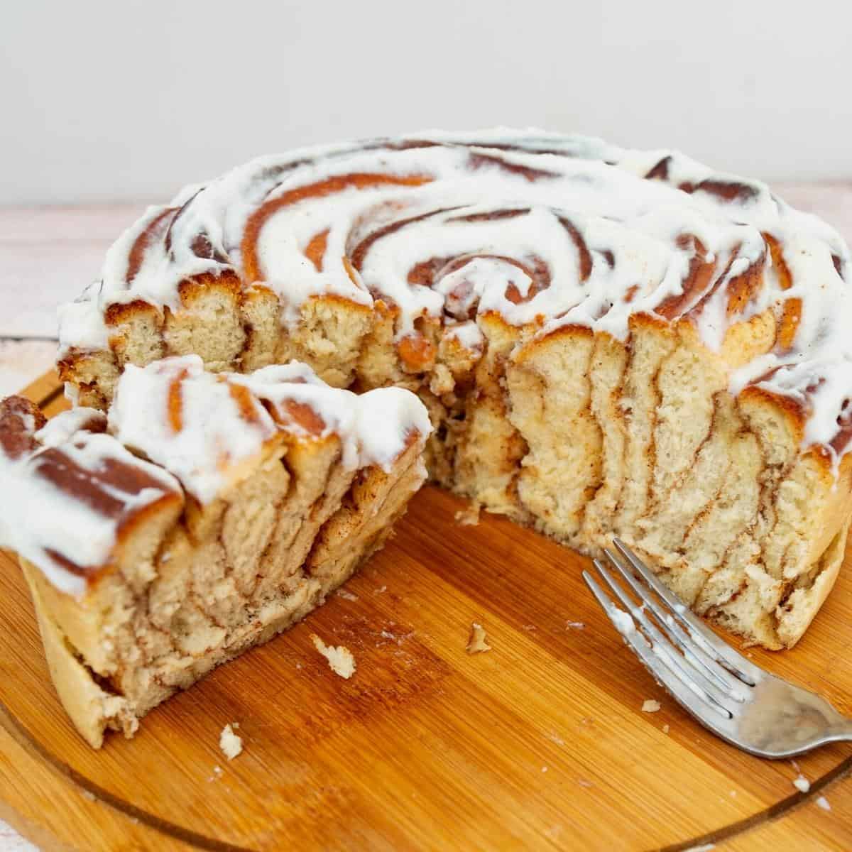 A sliced giant cinnamon roll on the wooden board.