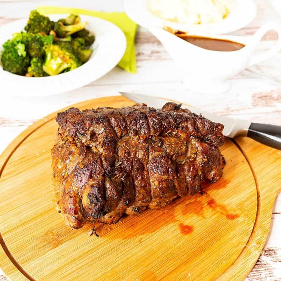 Beef roast resting on a wooden platter.