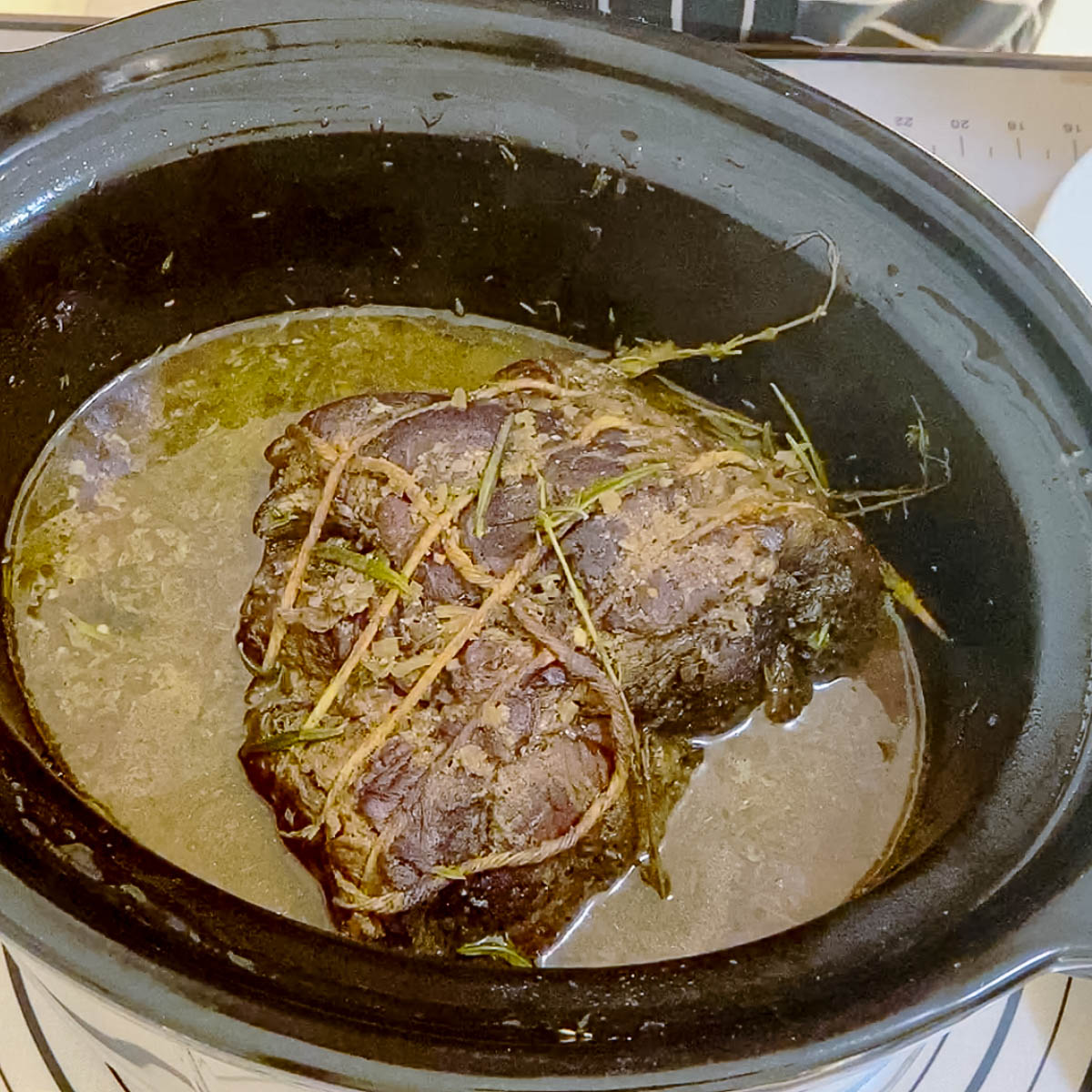 A crock pot with beef and sauce.