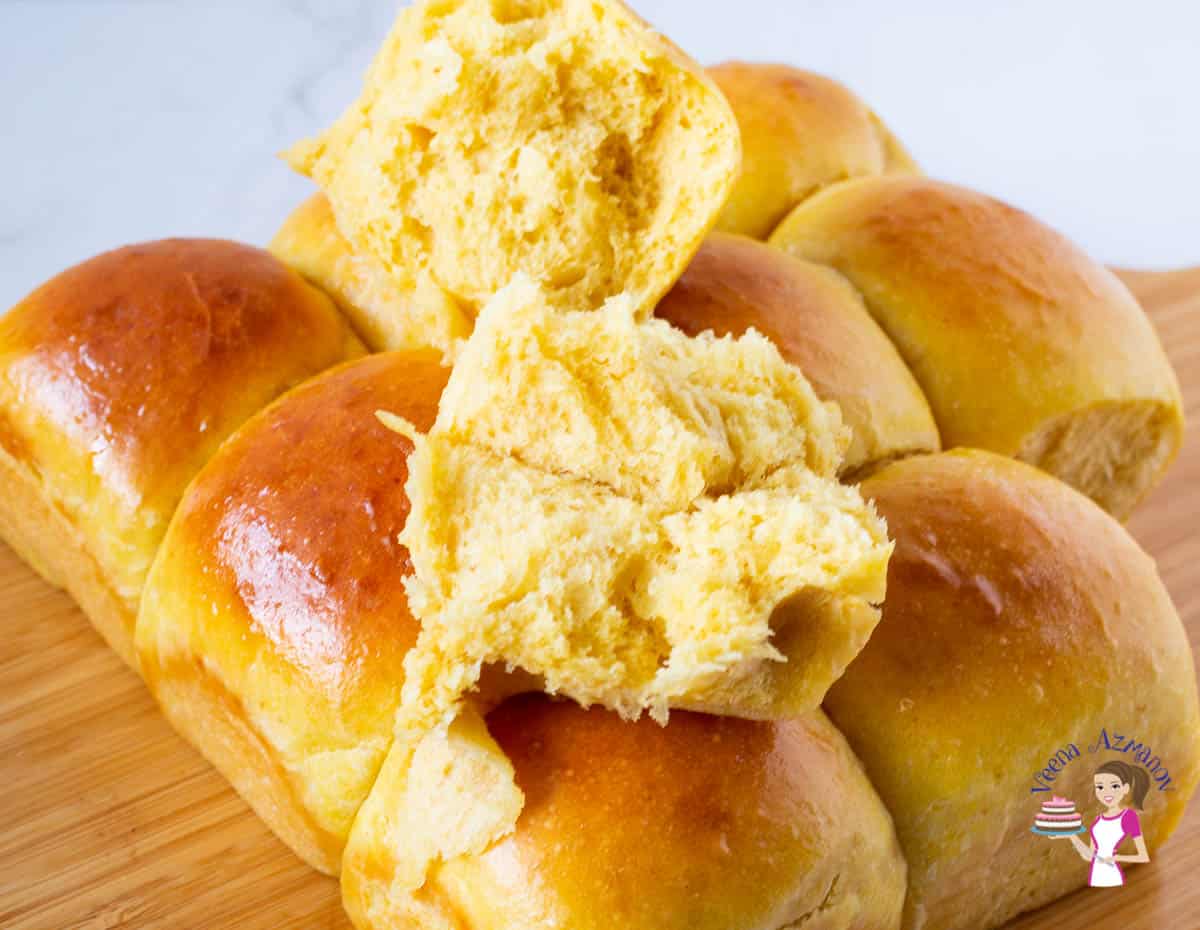A broken bread roll on top of other bread rolls