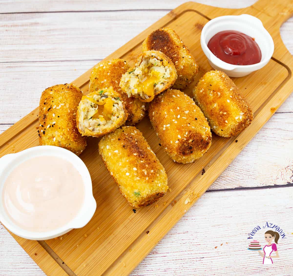 Chicken croquettes with dipping sauces on a wooden board.