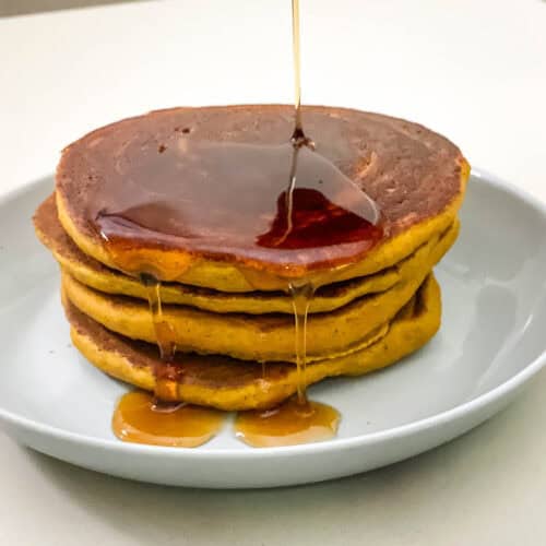 Pouring maple syrup on pancakes.