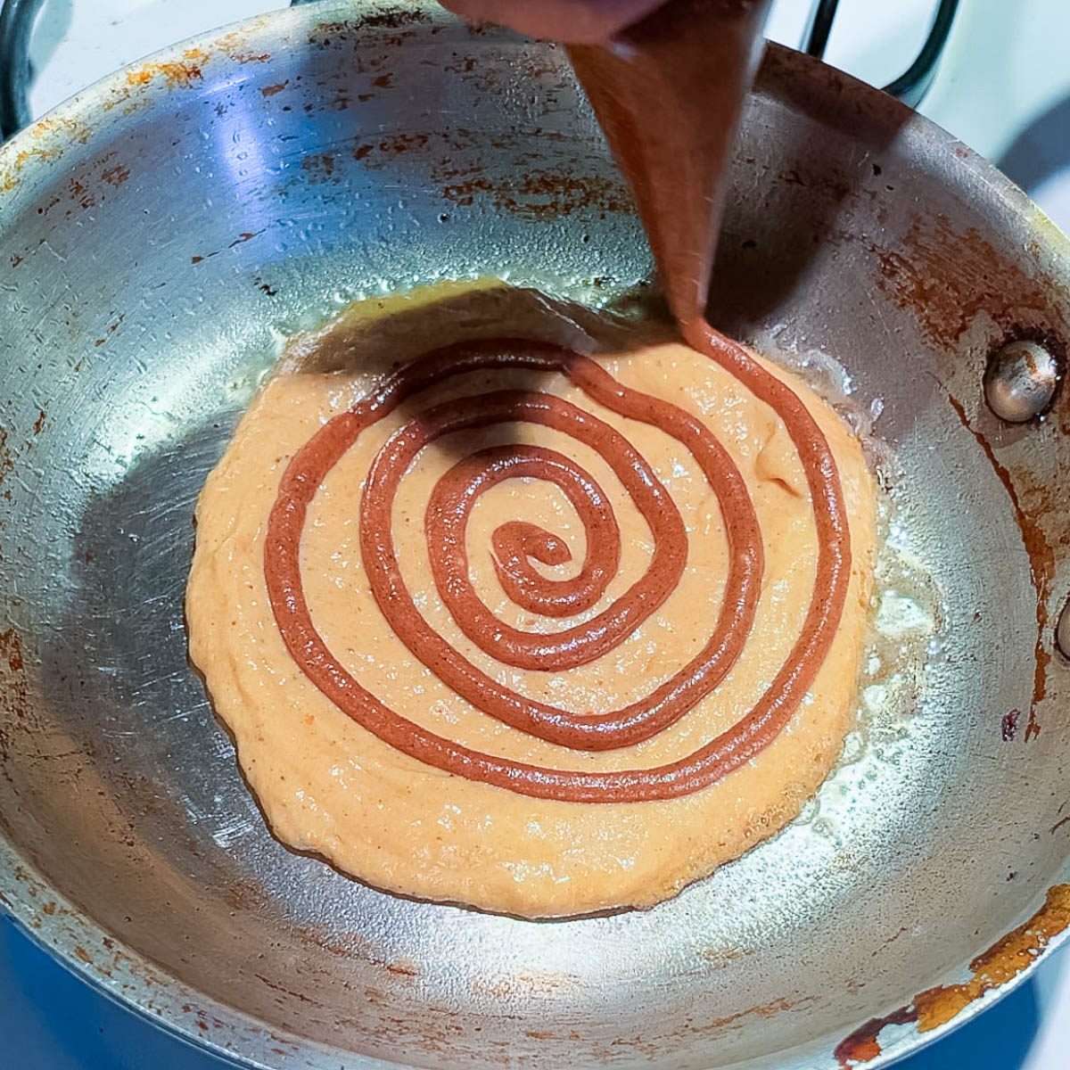 Piping cinnamon butter swirl on the frying pan.