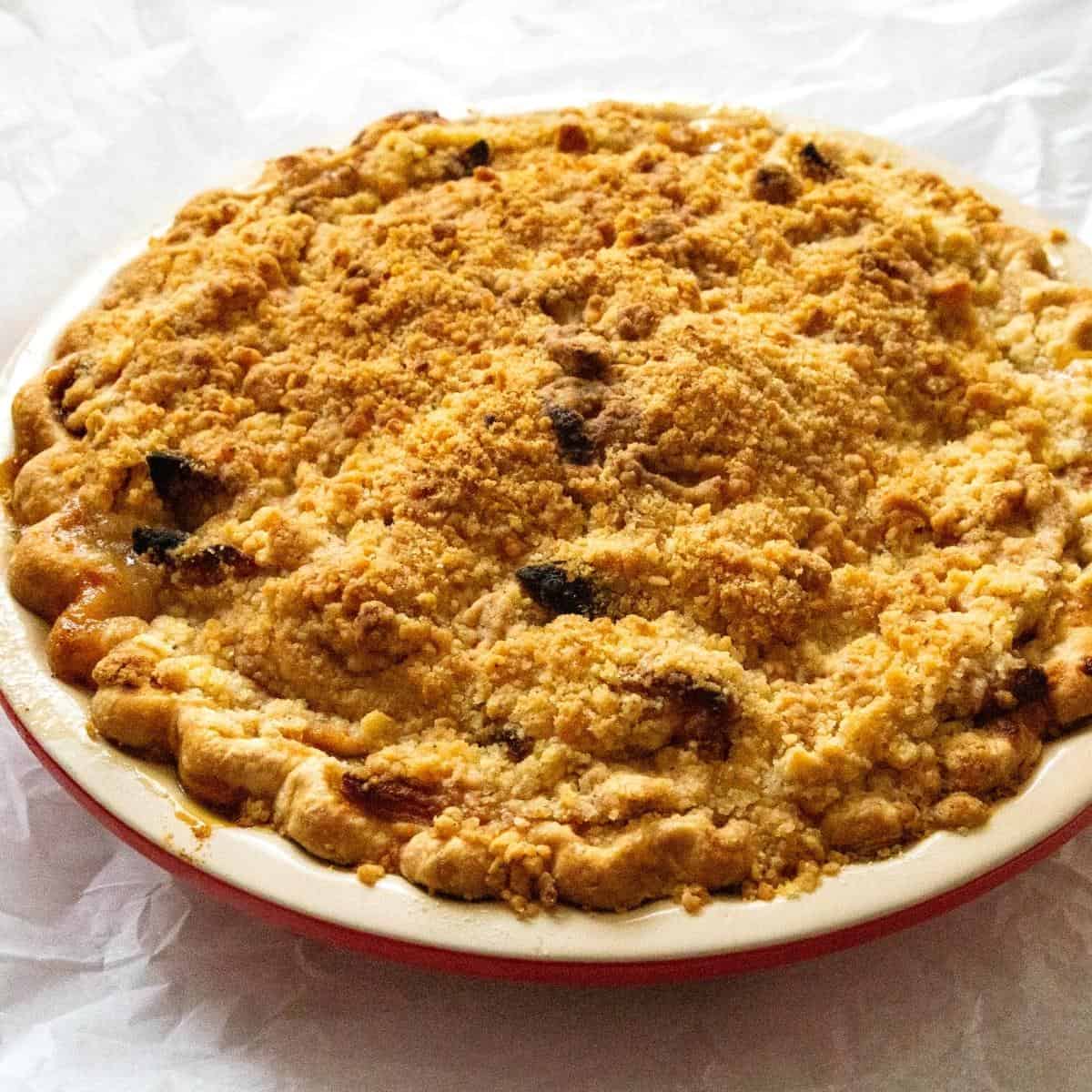 A pie pan with apple and crumbles.