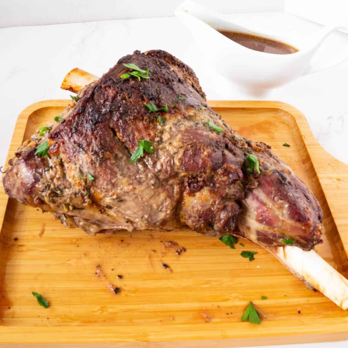 A wooden platter with roasted lamb.