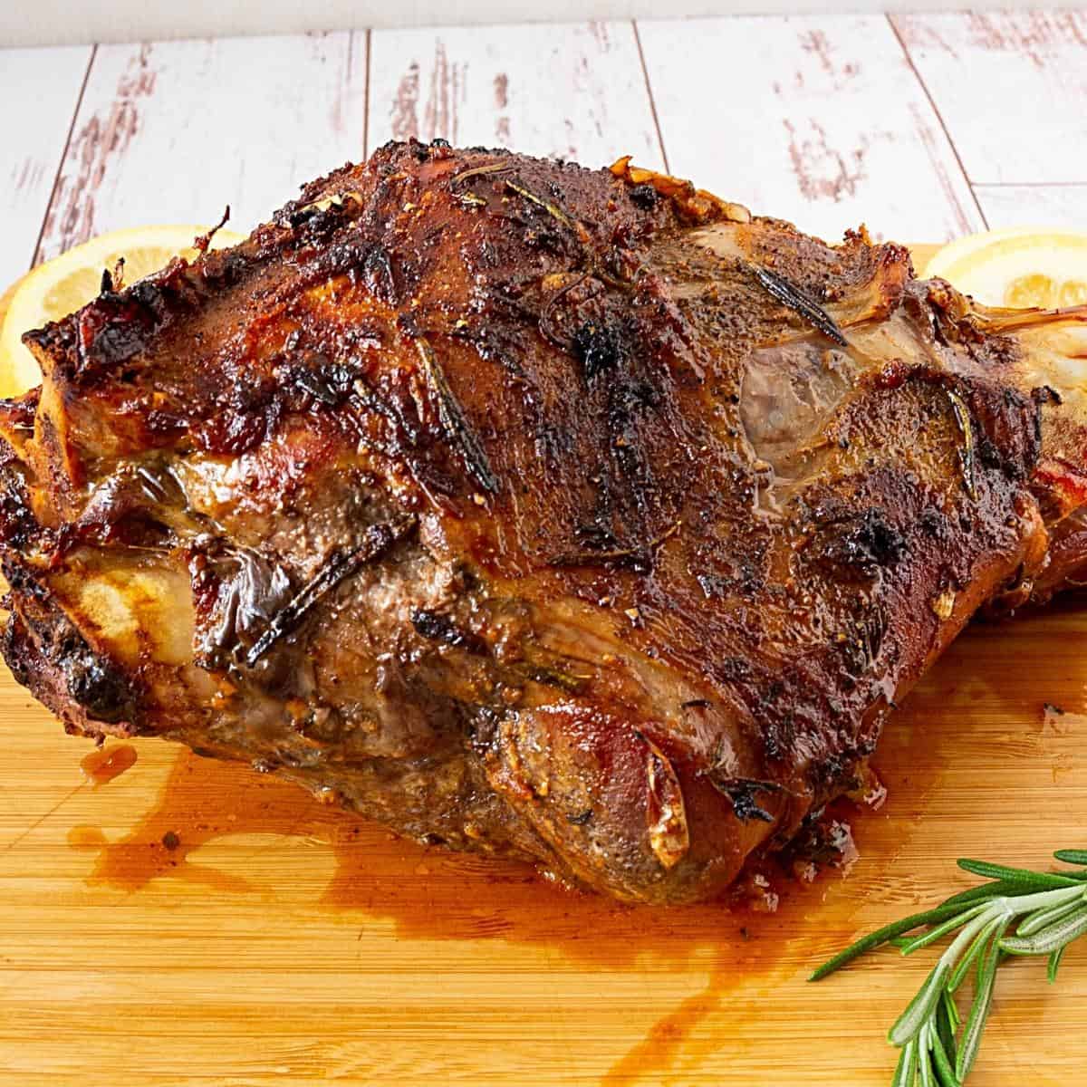 A roasted leg of lamb on a wooden board.