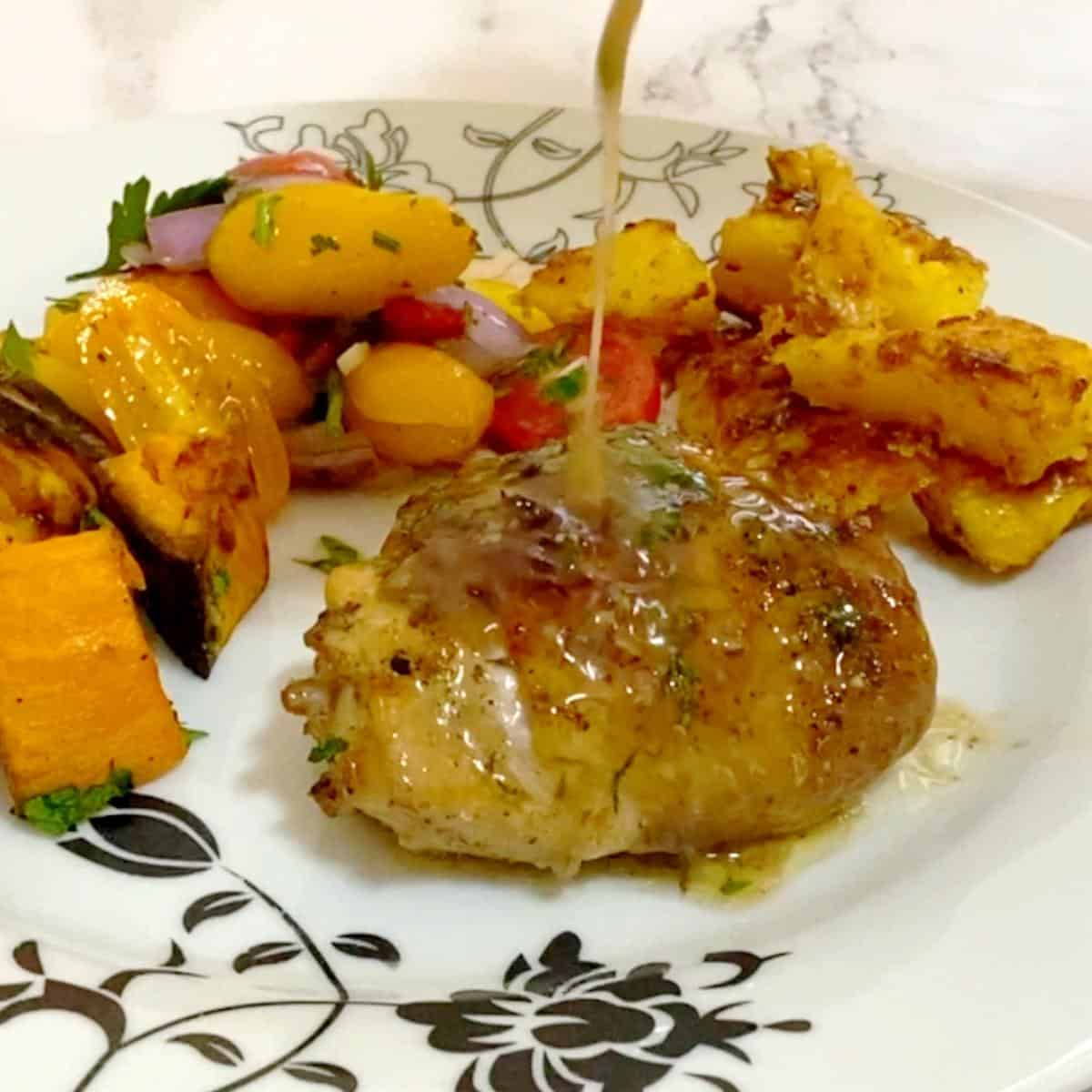 A plate with chicken thigh with pan juices.