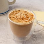 A chai latte in a glass cup on a marble surface