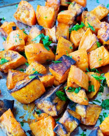 A baking tray with cubes of roasted sweet potatoes.