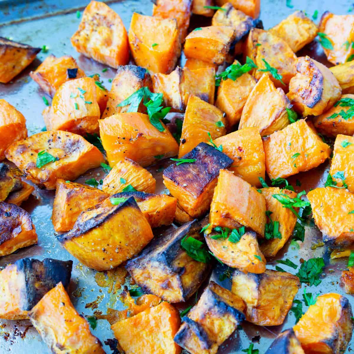 A baking tray with cubes of roasted sweet potatoes.