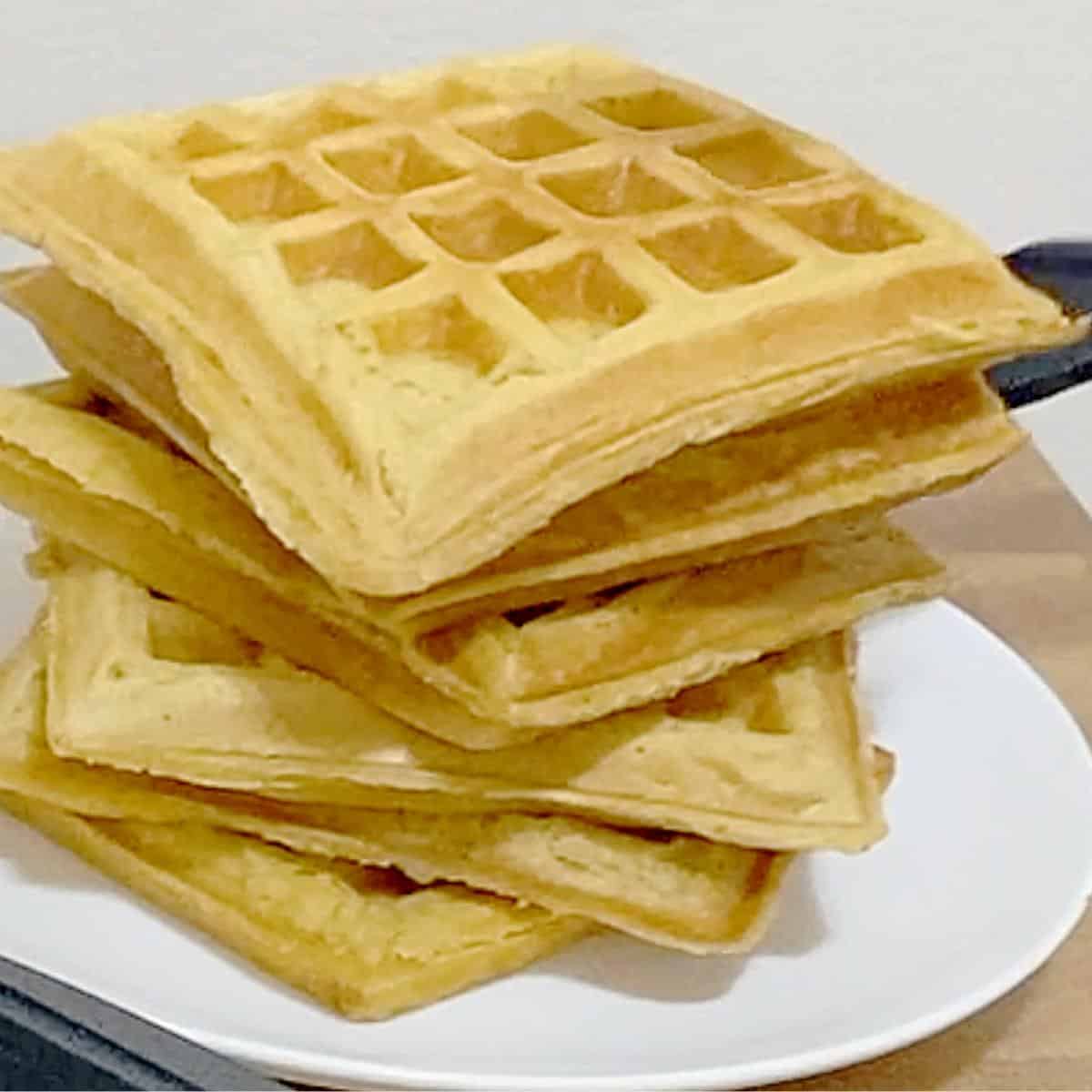 A stack of waffles on a plate.