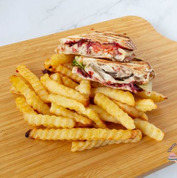 A wooden board with sandwich and fries