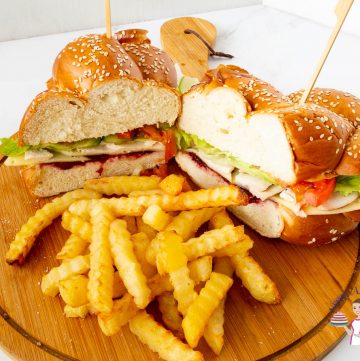 A cut sandwich with fries on a wooden board