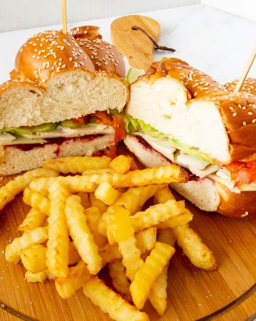 A cut sandwich with fries on a wooden board