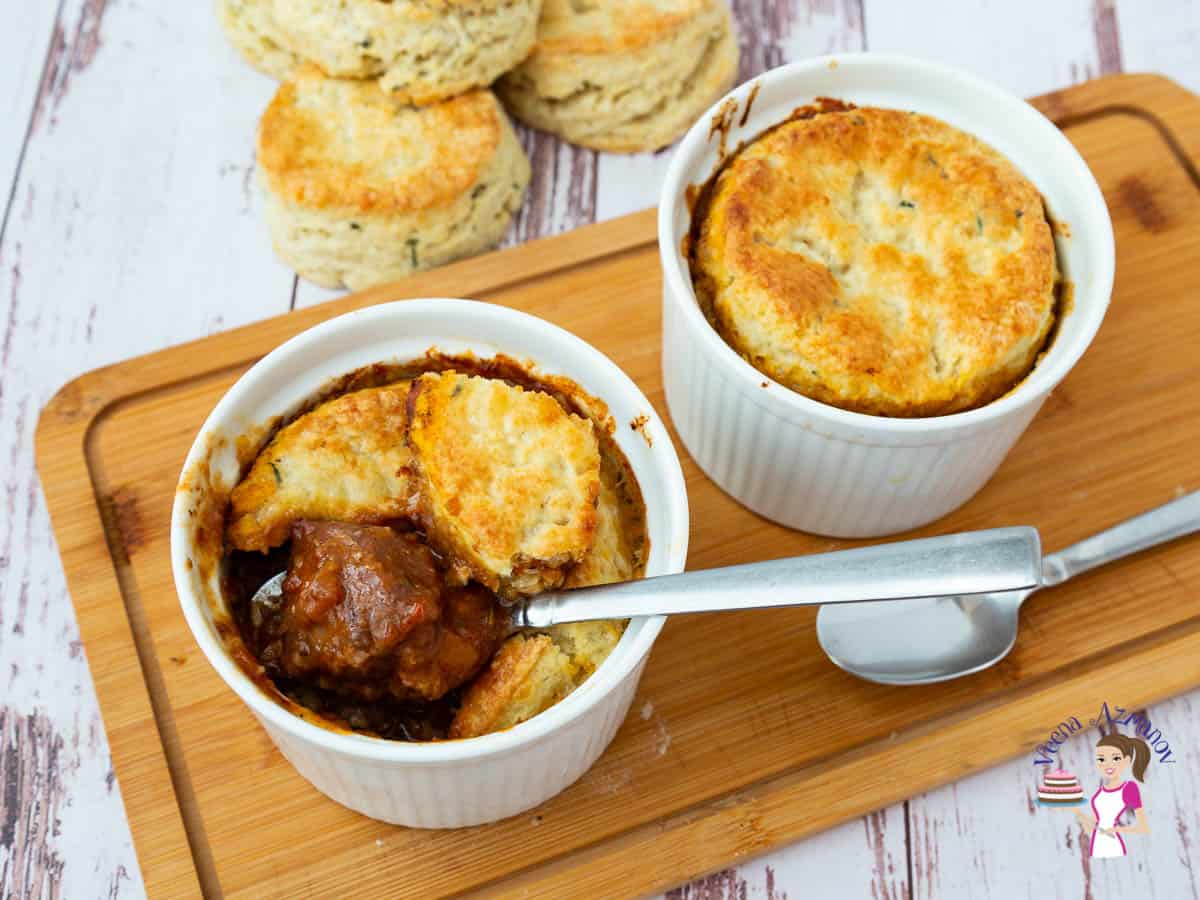 Two white ramekins with pot pie on a wooden board
