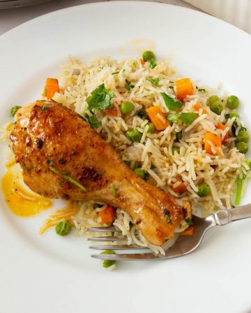 Rice pilaf and chicken drumstick on a plate.