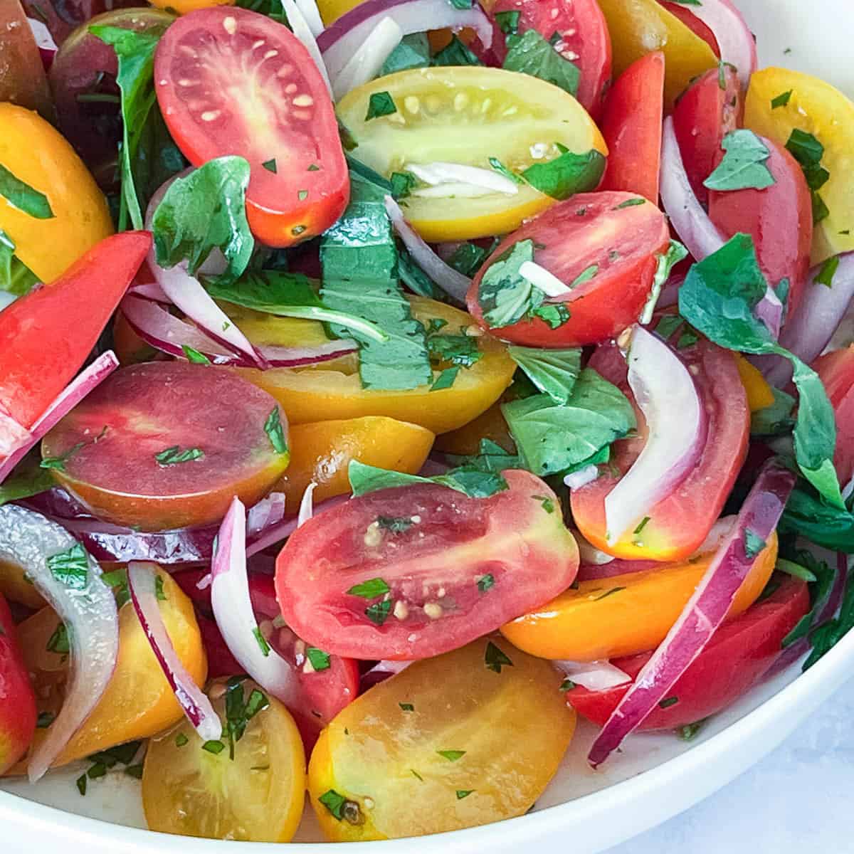A white plate with cherry tomato salad.