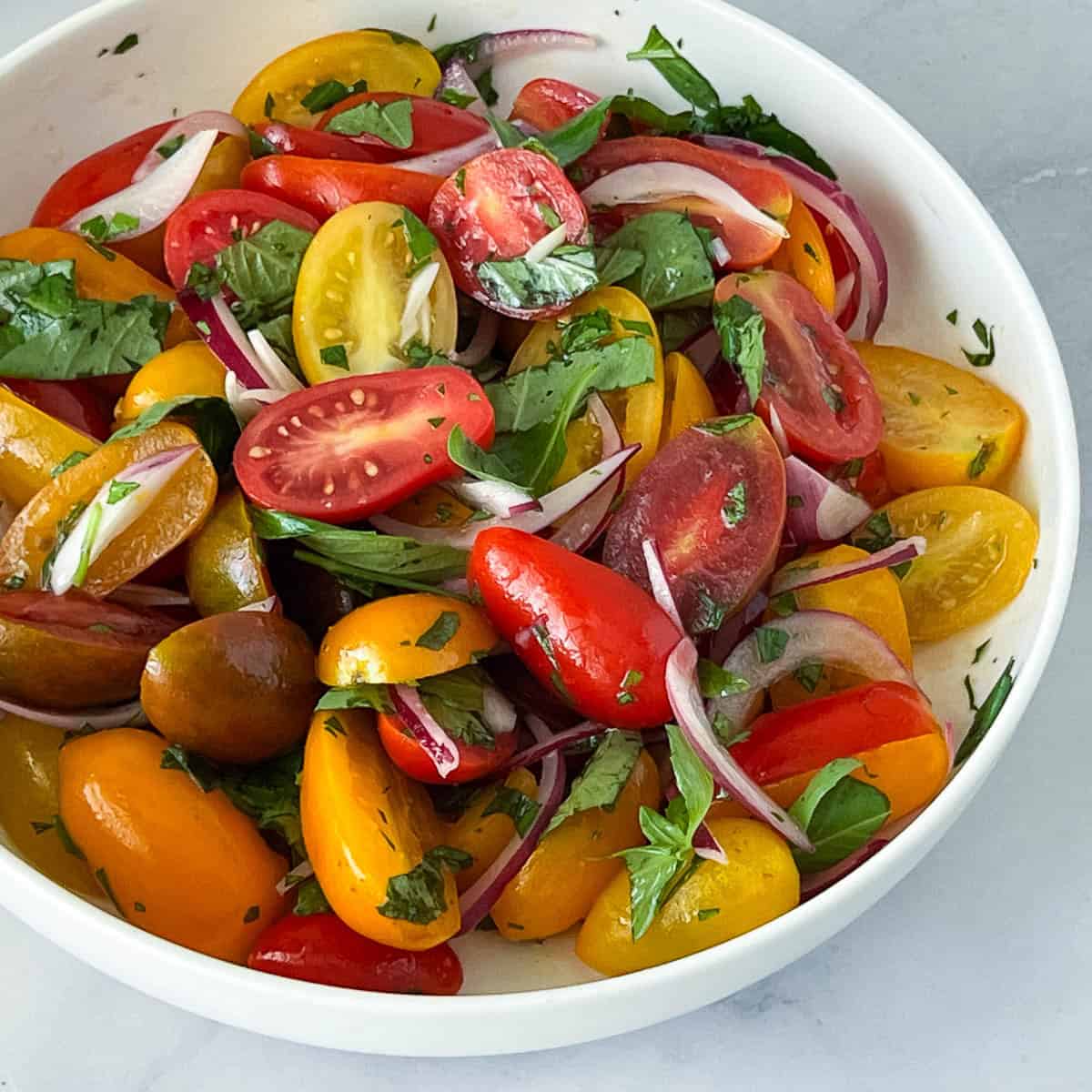 A cherry tomato salad in a white plate.