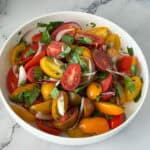 A white plate with fresh cherry tomatoes.