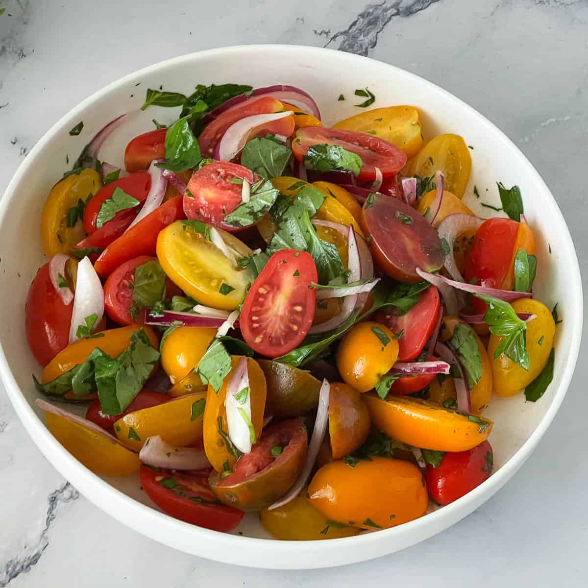 A white plate with fresh cherry tomatoes.